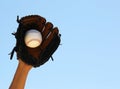 Hand of Baseball Player with Glove and Ball over Sky