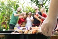 Hand of bbq grilling and friends having barbecue party, outdoors. Royalty Free Stock Photo