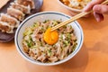 A hand beating yolk on Butadon: Japanese rice bowl dish consisting of pork and onion simmered together and served over rice.