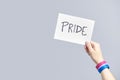 Hand with a bisexual flag bracelet holding a paper with a message: pride Royalty Free Stock Photo