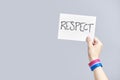 Hand with a bisexual flag bracelet holding a paper with a message: respect Royalty Free Stock Photo