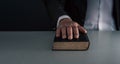 Hand on black book ,swearing on the bible , concept of telling the truth . on grey blue background Royalty Free Stock Photo