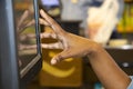 Hand of black girl cashier using touch screen cash register with blurred bokeh background - reflection of hand in screen