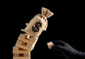 a hand with black glove damaging the foundation of an US money bag and made it fell down