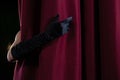 Hand in a black glove pulling curtain away Royalty Free Stock Photo