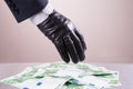 Hand in black glove steals money, bribe and corruption concept