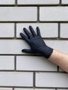 Hand in black gloves on a brick background