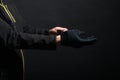 Hand in black gloves of a crime on a black background. Gloves are worn on the hand. The man puts a black glove on his Royalty Free Stock Photo