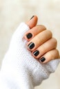 hand with black manicure on short nails in a white sweater on a light background. The concept of a stylish and warm winter Royalty Free Stock Photo