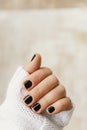 hand with black manicure on short nails in a white sweater on a light background. The concept of a stylish and warm winter Royalty Free Stock Photo