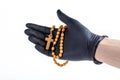 Hand in a black medical protective latex glove holding up a simple wooden christian rosary with a cross isolated on white, cut out Royalty Free Stock Photo