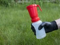 Hand in black nitrile glove holding a teat dip cup for udder cow disinfection on green grass background, copy space. Milking Royalty Free Stock Photo