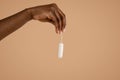 Hand of black woman holding tampon over beige studio background Royalty Free Stock Photo