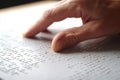 Hand of a blind person reading some braille text touching the relief