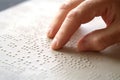 Hand of a blind person reading some braille text touching the relief