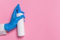 Hand in blue disposable glove holding surface disinfectant or hand sanitizer on pink background Royalty Free Stock Photo