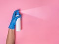 Hand in blue disposable glove overspraying surface disinfectant or hand sanitizer on pink background Royalty Free Stock Photo