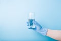 Hand in blue disposable medical glove holds a glass glass with water, Royalty Free Stock Photo