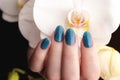 Hand with blue glitter nails with flower