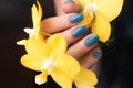 Hand with blue glitter nails with flower