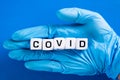 Hand in blue glove with Covid word. COVID-19 pandemic concept