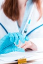 The hand in blue glove holding syringe against white medical gown Royalty Free Stock Photo