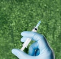 Hand with blue glove holding a syringe green background Royalty Free Stock Photo