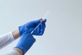 Hand in blue glove holding a syringe on grey background. Royalty Free Stock Photo