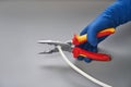 Hand in blue glove holds pliers electrician and cutting cable Royalty Free Stock Photo