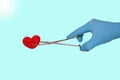 Hand in a blue glove holds a stethoscope red heart isolated on a blue background, surgeon doctors save lives, toned