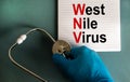 Hand in blue glove with stethoscope, white card with words `West Nile virus`. Medical epidemic concept