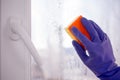 Hand blue glove washes window with yellow sponge Royalty Free Stock Photo