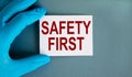 Hand in blue glove with white card. Concept words `safety first`. Medical concept