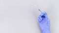 Hand in blue gloves of doctor or nurse holding syringe with liquid vaccine over grey background with copy space. New vaccine. Royalty Free Stock Photo