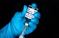 Hand in blue gloves holding hypodermic syringe and coronavirus vaccine sticker own design, not real product, injecting it Royalty Free Stock Photo
