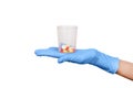 Hand in blue latex medical glove holding a lot of pills in medical glass isolated on white. Close up. Medicine or health treatment Royalty Free Stock Photo