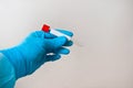 Hand in blue medical disposable rubber gloves holding a blank test tube to collect analyzes on a gray background Royalty Free Stock Photo