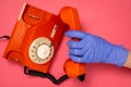 Hand in blue medical glove holding old telephone receiver Royalty Free Stock Photo