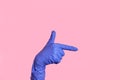 A hand in a blue medical, surgical glove shows a gun gesture or to the right. Royalty Free Stock Photo