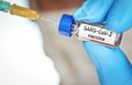 Hand in blue nitrile glove hold small vial with coronavirus vaccine, to inject it with hypodermic syringe needle, blurred face Royalty Free Stock Photo