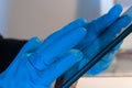 Hand with a blue nitrile glove using a tablet