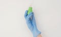 Hand in a blue rubber glove holding a green ampule on white background Royalty Free Stock Photo