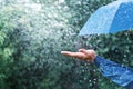 Hand And Blue Umbrella Under Heavy Rain Against Nature Background. Rainy Weather Concept