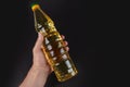 Hand with bottle of cooking oil on blsck background Royalty Free Stock Photo