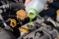 Hand with bottle pouring antifreeze coolant into the expansion tank. Dusty details of a flat-four boxer car engine compartment Royalty Free Stock Photo