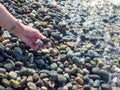 A hand with a bracelet made of stones holds a pebble near the water. Sea wave and female hand. Feel the wave. Pebble beach Royalty Free Stock Photo