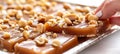 Hand breaking crunchy peanut brittle, highlighting texture and peanuts, on bright white background