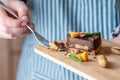 Hand breaks with a fork a piece of chocolate cake with orange, mint leaves and nuts. Healthy raw desserts for vegan food Royalty Free Stock Photo