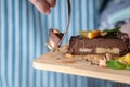 Hand breaks with a fork a piece of chocolate cake with orange, mint leaves and nuts. Healthy raw desserts for vegan food Royalty Free Stock Photo