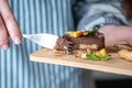 Hand breaks with a fork a piece of chocolate cake with orange, mint leaves and nuts. Healthy raw desserts for vegan food Royalty Free Stock Photo